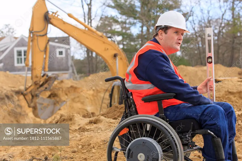 Construction engineer with spinal cord injury holding level at site