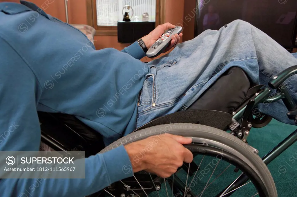 Man with spinal cord injury in a wheelchair using a remote control