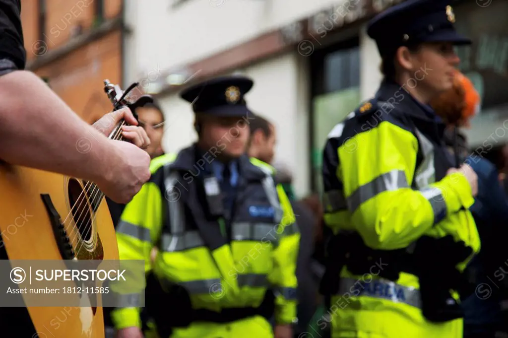 Dublin, Ireland, A Musician Plays His Guitar In The Street As The Police Pass By