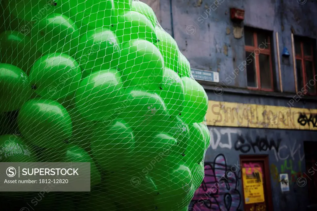 Dublin, ireland, a large bundle of green balloons by a building covered in graffiti