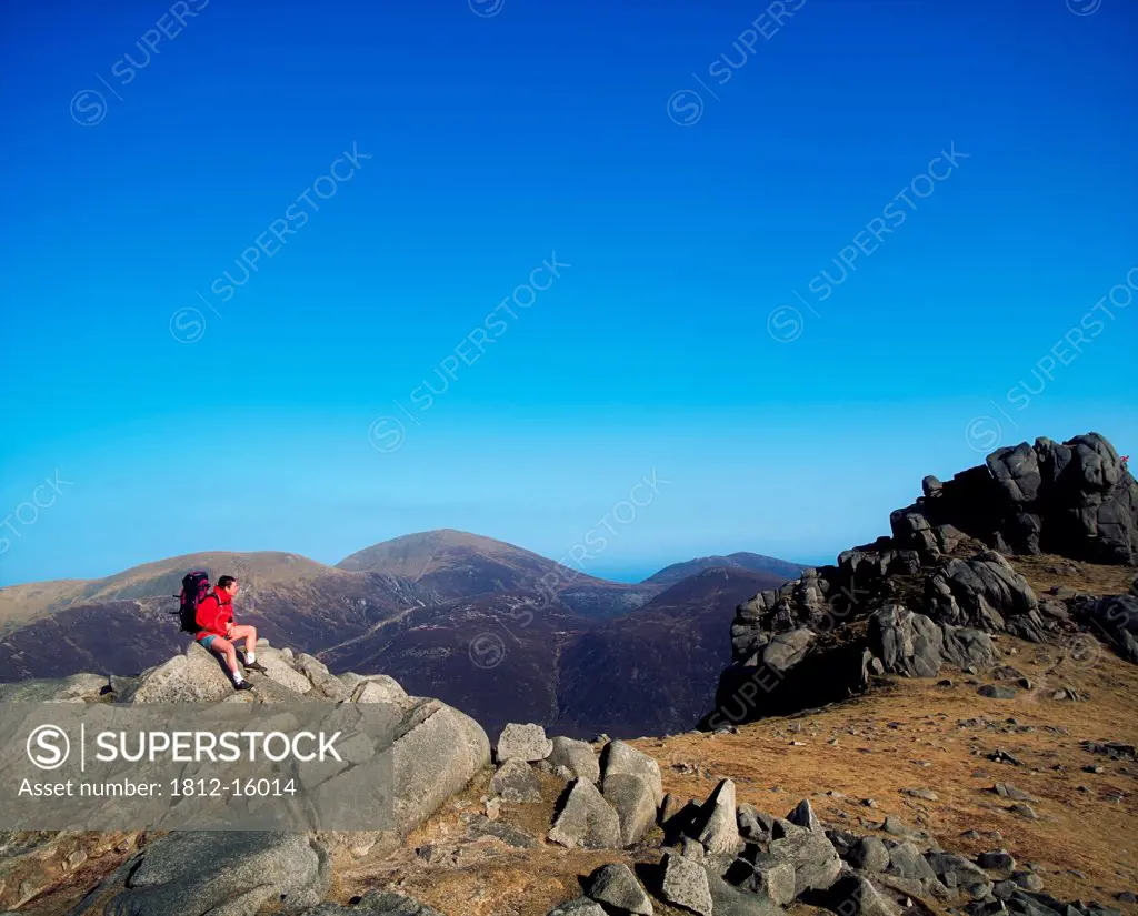 Tourists Sitting On A Rock Formation, Mountains Of Mourne, County Down, Northern Ireland