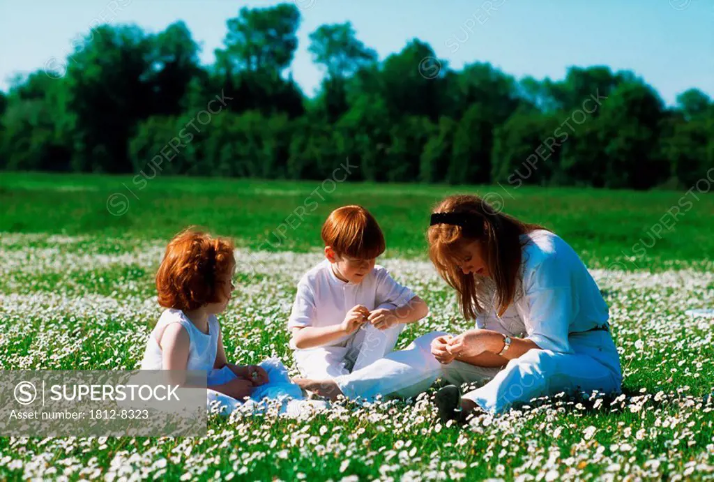 Mother making daisy chains with her children