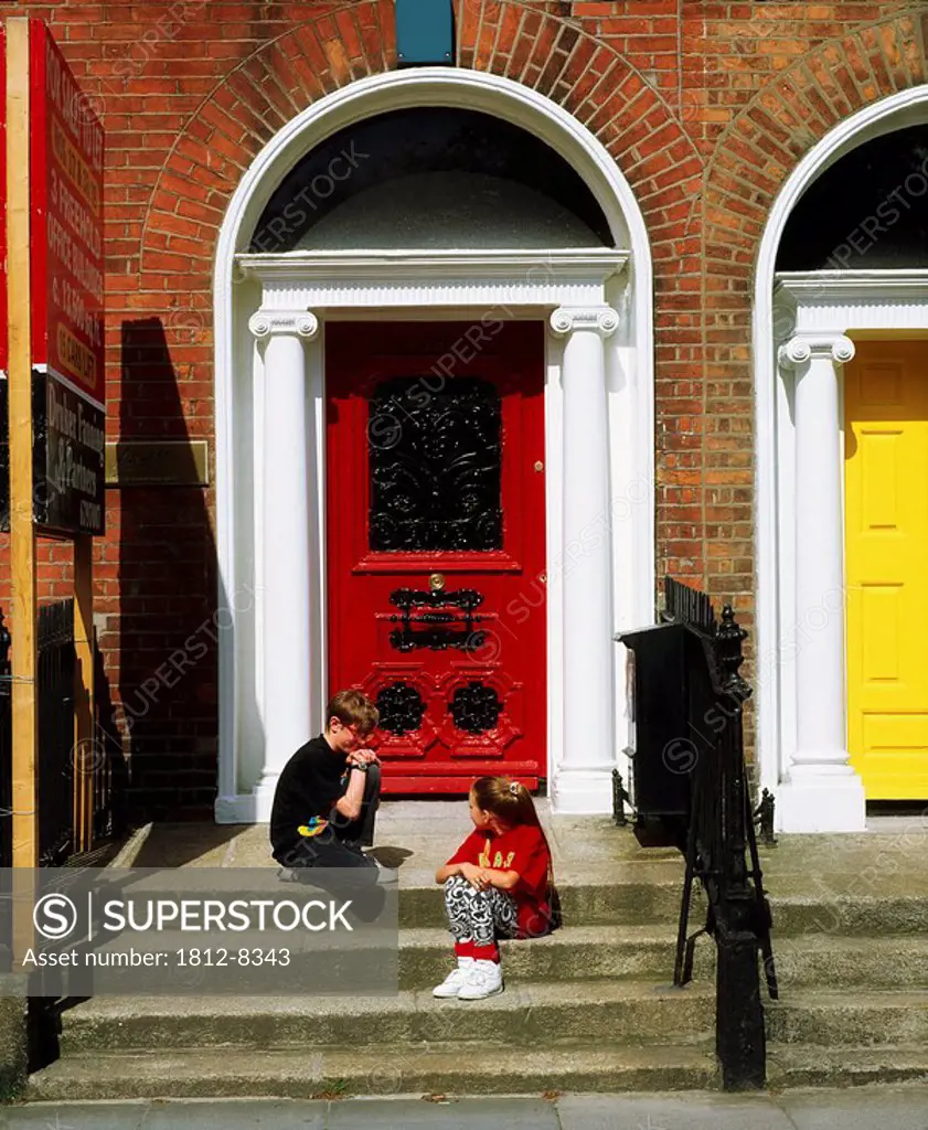 Children sitting in front of Georgian doors, Fitzwilliam Square, Dublin, Co Dublin, Ireland