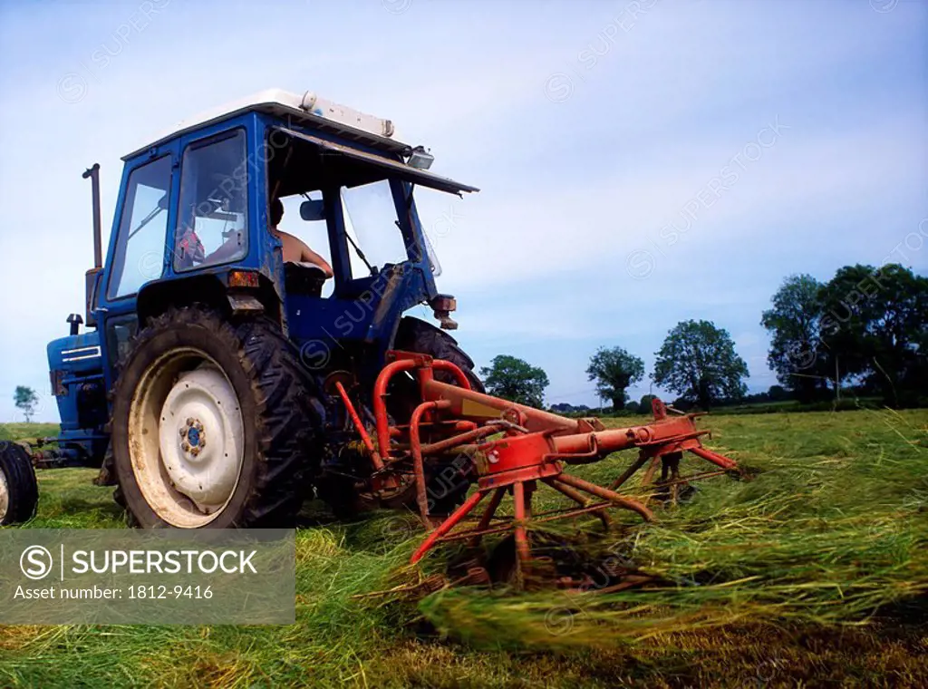 Man turning hay in field with tractor, Agriculture