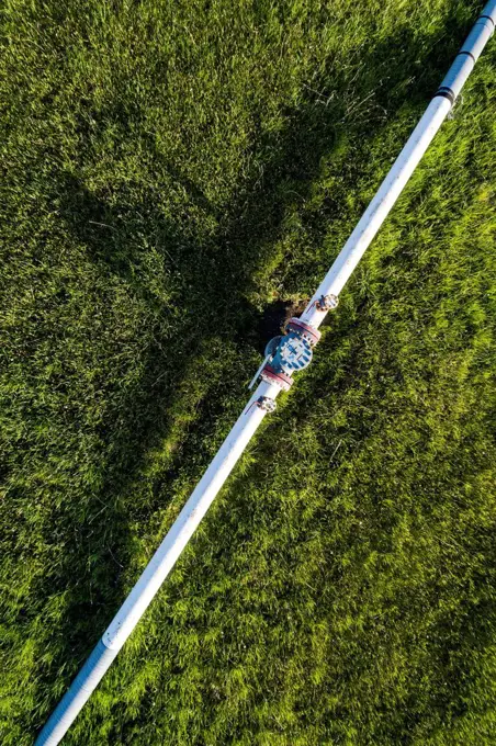 Aerial view of a pipeline with a value and coupling in a green field, West of Calgary; Alberta, Canada
