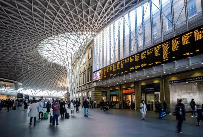 Interior of London King's Cross railway station with travellers and shops; London, England