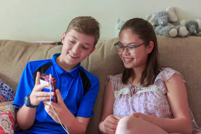 Teenage girl who has Learning Disability looking at phone with her brother