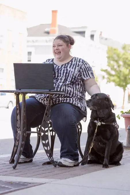 Woman with Visual Impairment sitting at a café with her computer and service dog