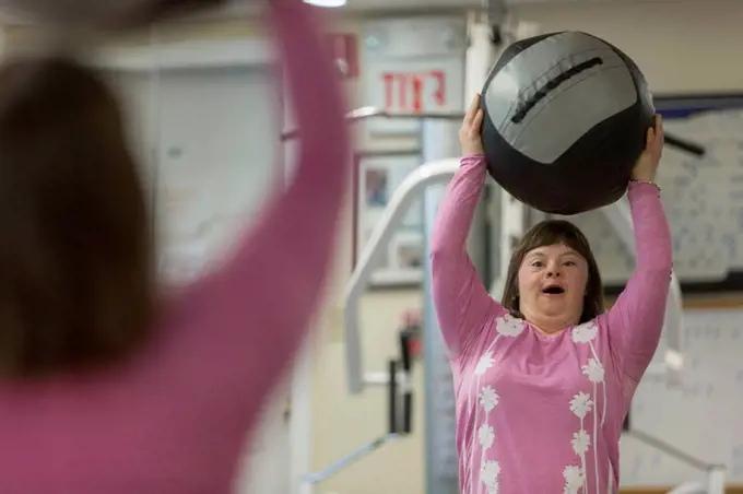 Girl with Down Syndrome working out with an exercise ball