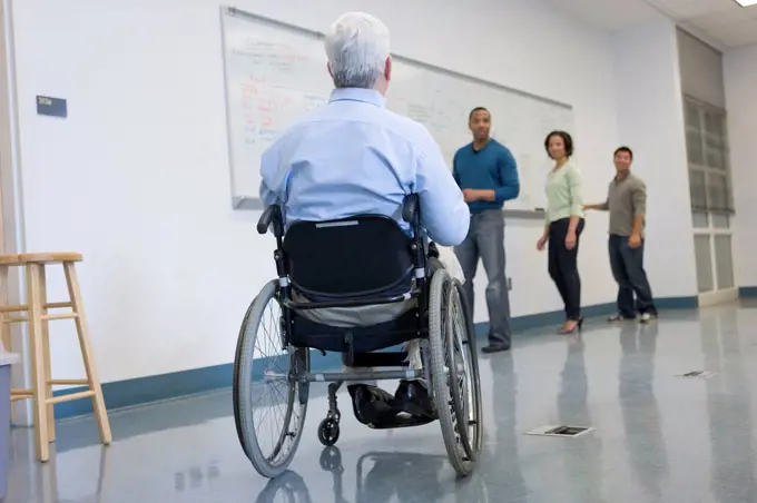 University professor with Muscular Dystrophy with his students in a classroom
