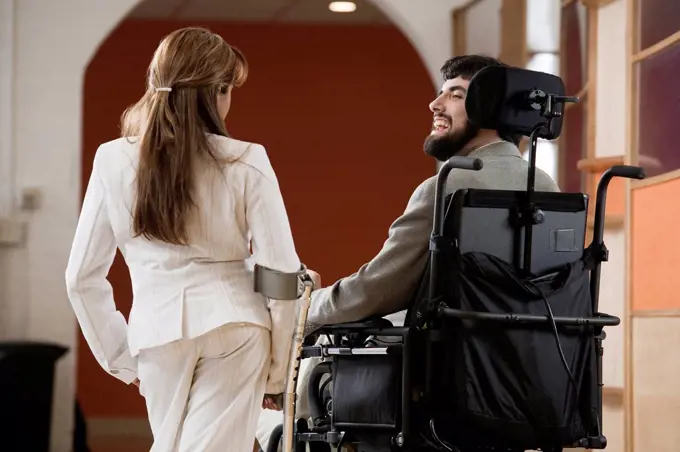 Man with Cerebral Palsy and woman with cane conversing.