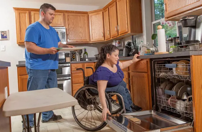 Woman with Spina Bifida and her husband using the dishwasher in kitchen
