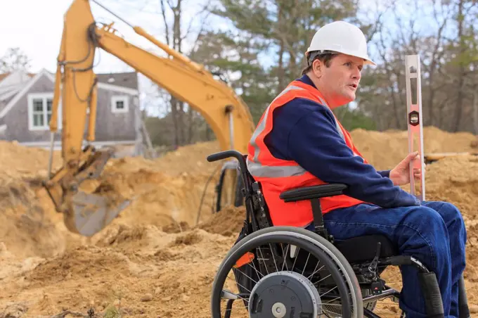 Construction engineer with spinal cord injury holding level at site