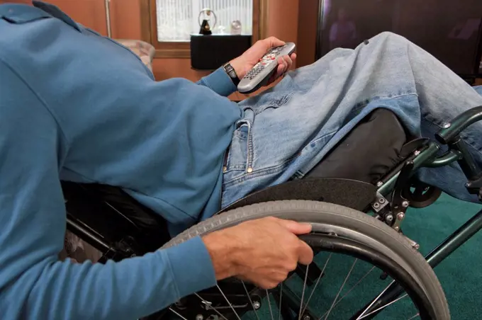 Man with spinal cord injury in a wheelchair using a remote control