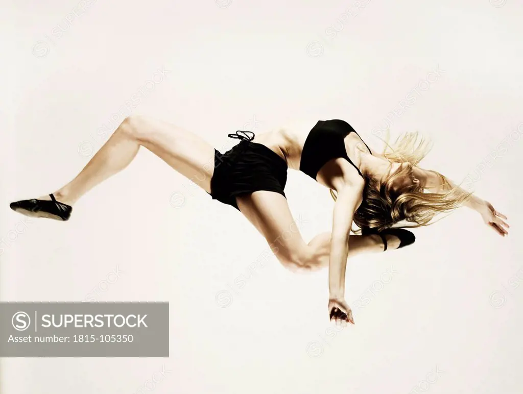 Young woman in sportswear jumping against white background
