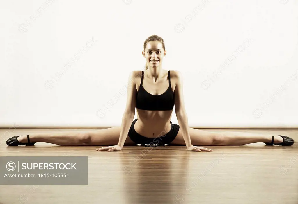 Young woman in sportswear stretching against white background