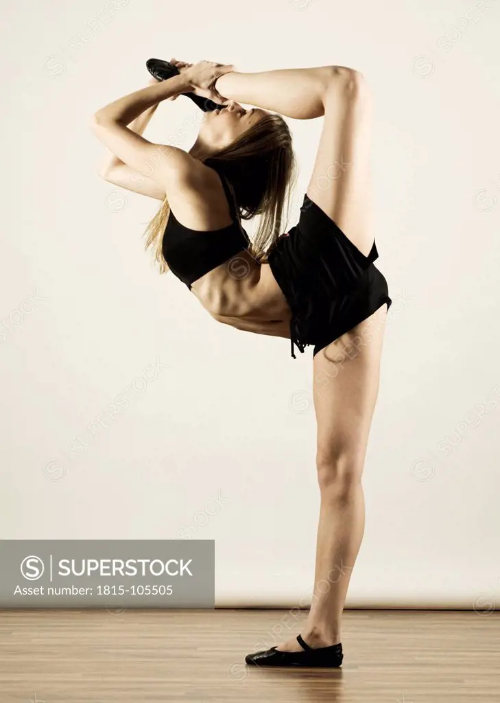 Young woman in sportswear stretching against white background