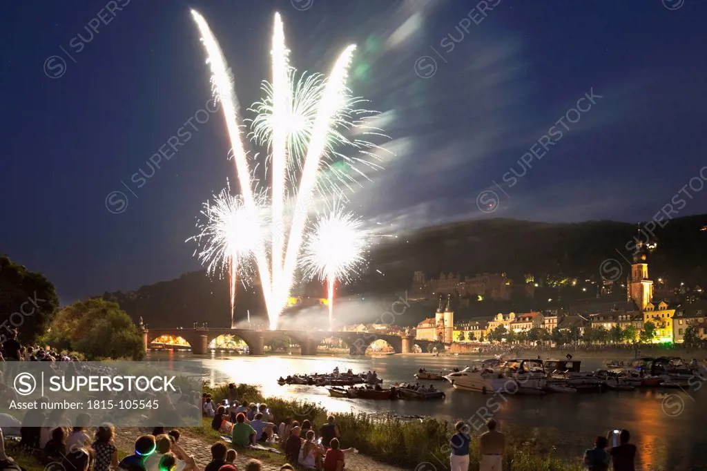 Germany, Heidelberg, People watching fireworks with city in background