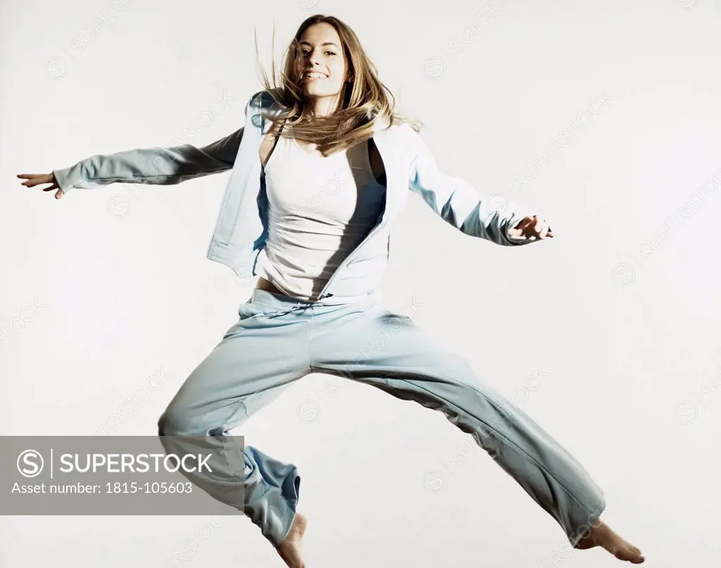 Young woman in sportswear jumping against white background