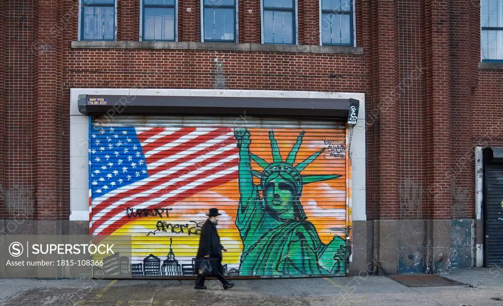 USA, New York, Man walking in front of patriotic graffitti on shutter