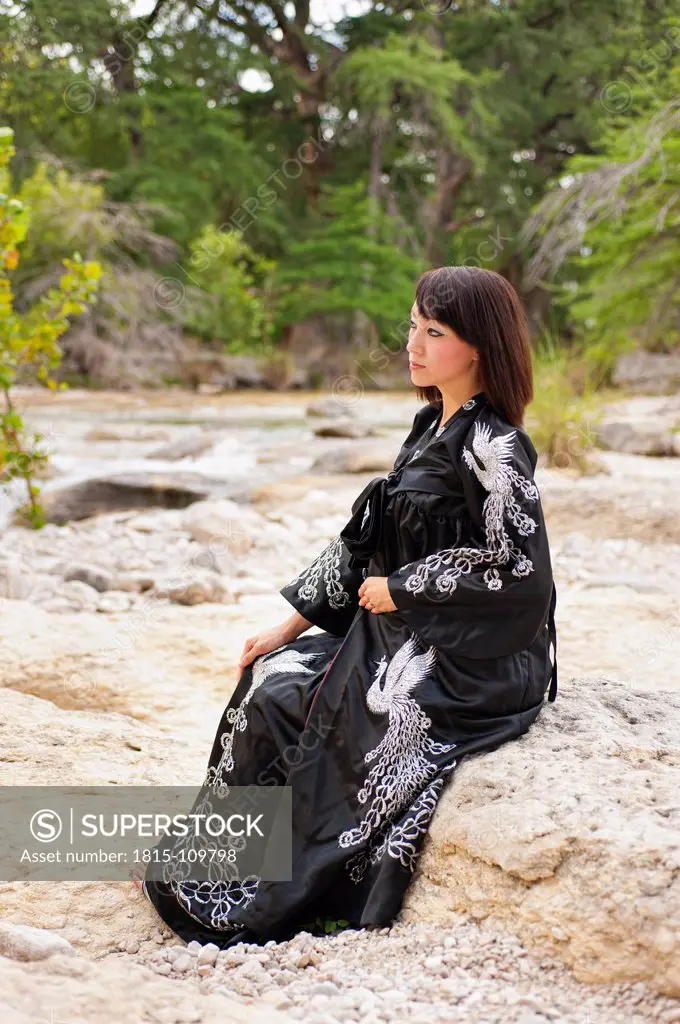USA, Texas, Leakey, Young woman sitting at Frio River