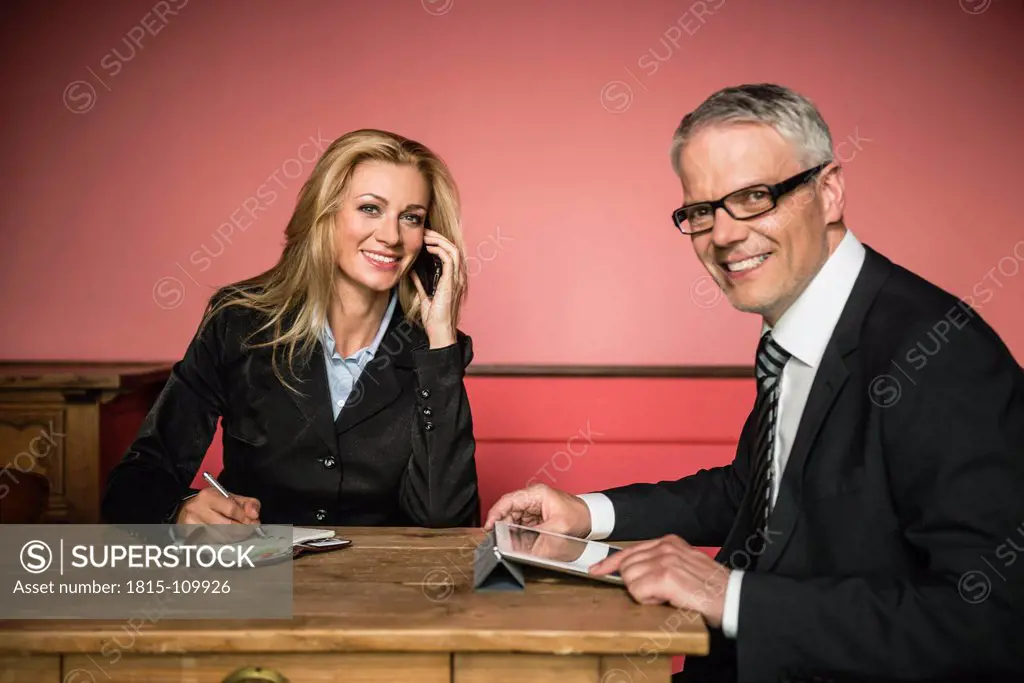 Germany, Stuttgart, Businessman with digital tablet while woman talking on phone