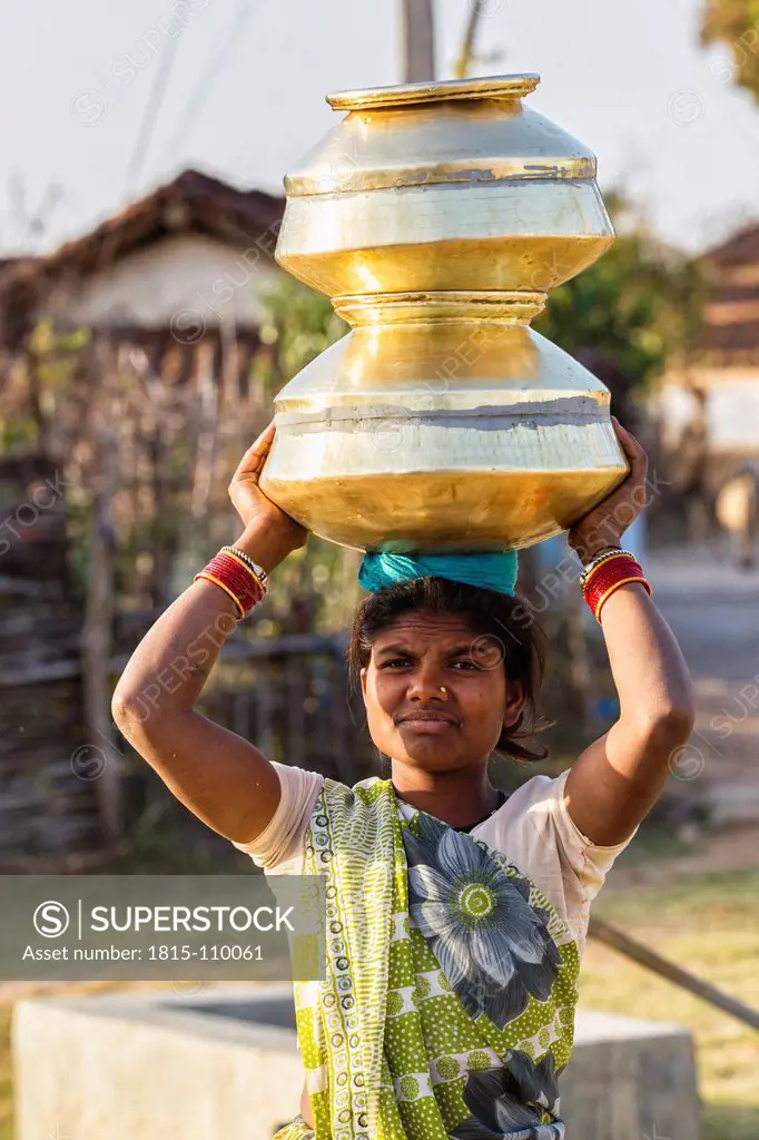 India, Madhya Pradesh, Woman carrying big water pots on her head