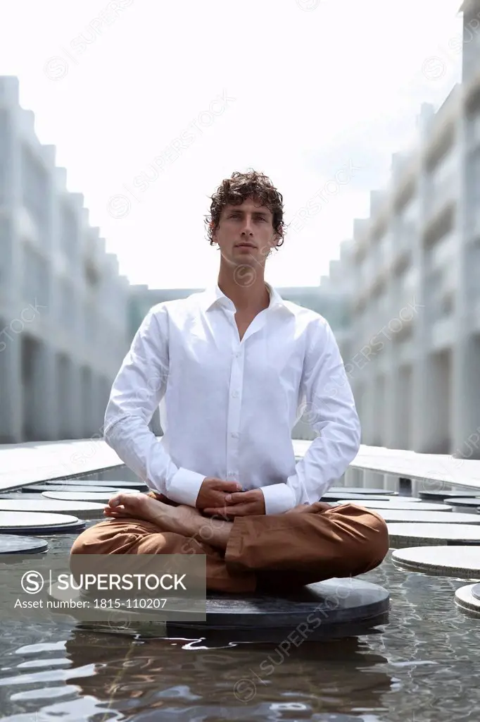 Germany, Bavaria, Young business man relaxing with yoga