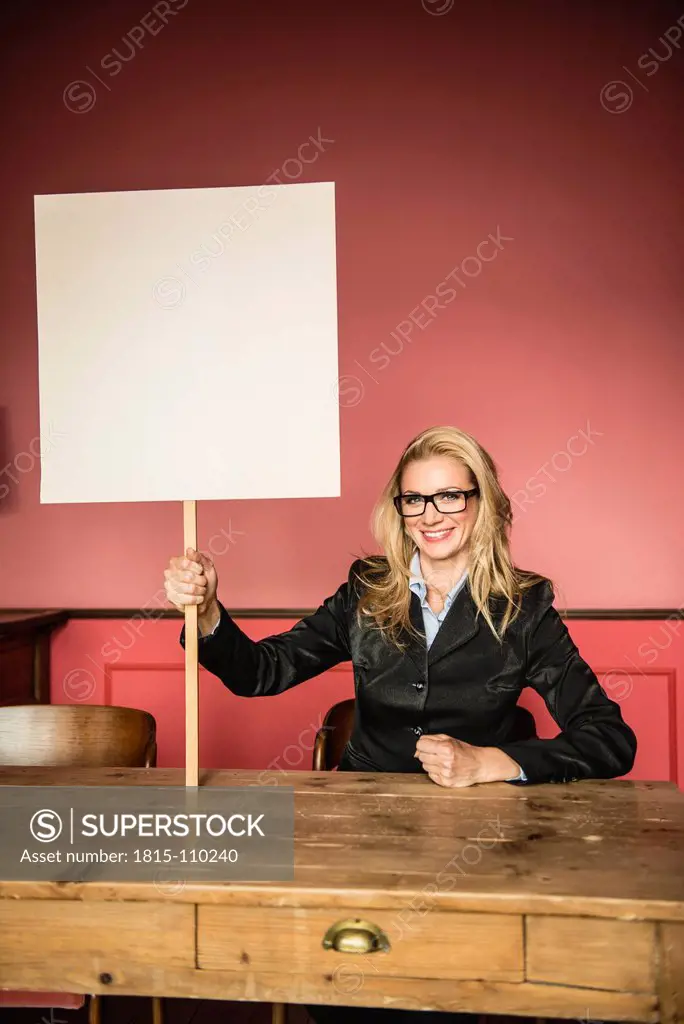 Germany, Stuttgart, Businesswoman holding blank sign, smiling, portrait
