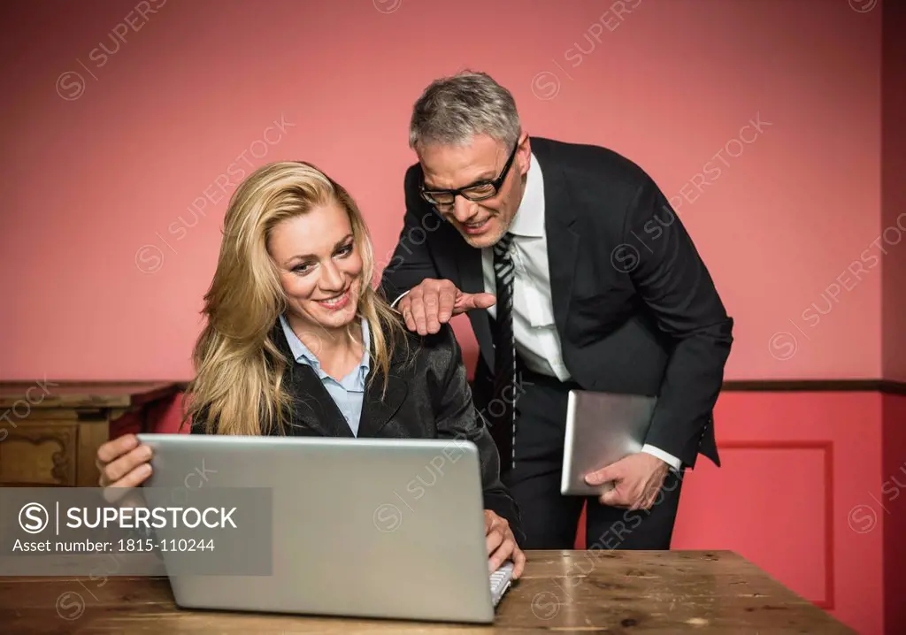 Germany, Stuttgart, Businessman and woman working on laptop, smiling