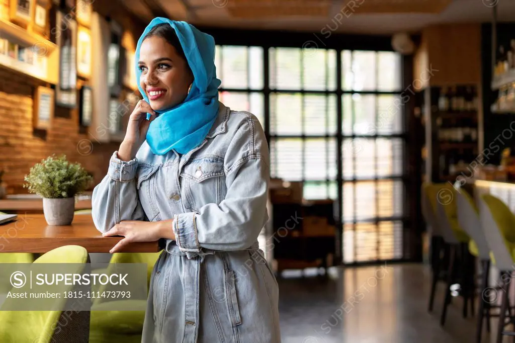 Young woman wearing turquoise hijab in a cafe