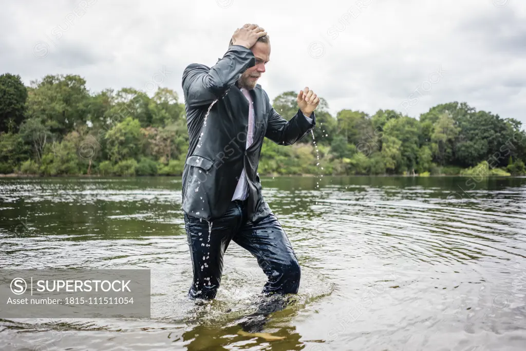 Wet businessman walking in a lake