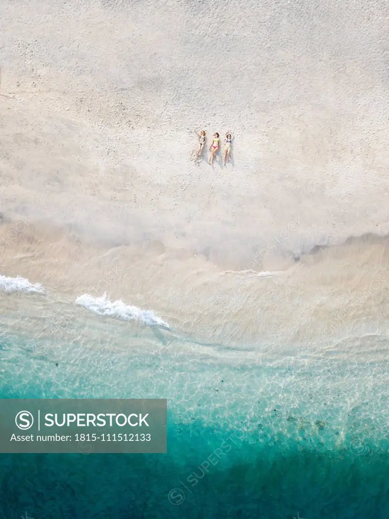 Aerial view of young women lying at the beach, Gili Air island, Bali, Indonesia