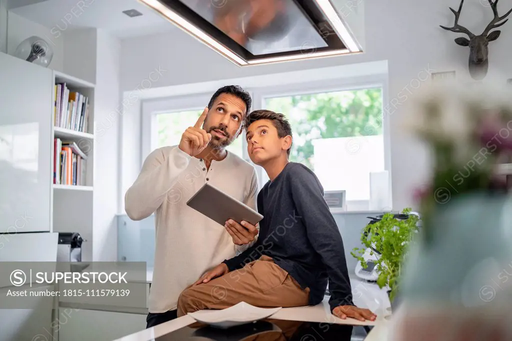 Father and son using tablet in kitchen