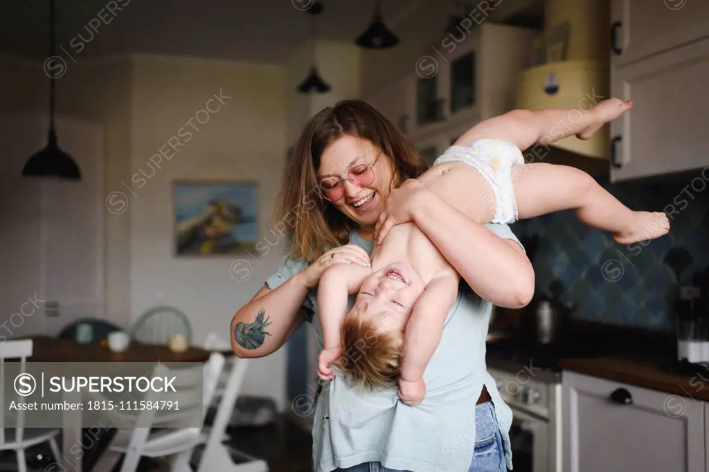 Portrait of mother playing with her little son in the kitchen