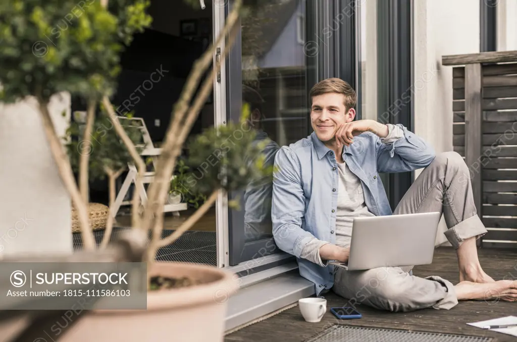 Man sitting on terrace, using laptop