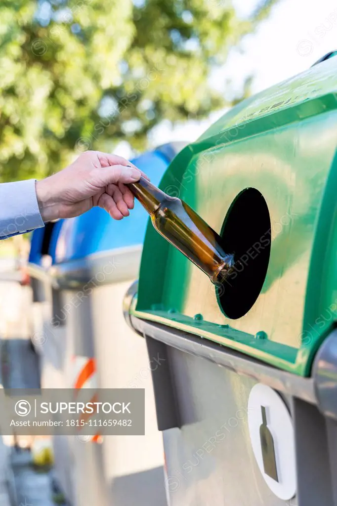 Close-up of man putting bottle into bottle bank