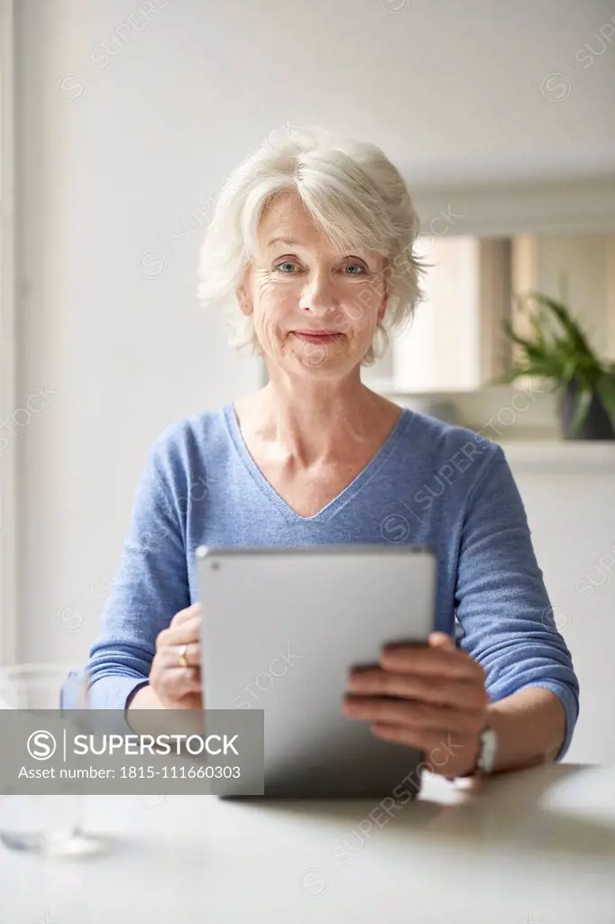 Portrait of smiling mature woman using digital tablet at desk