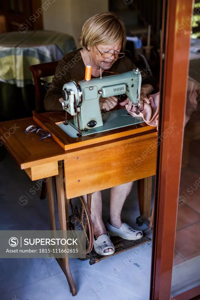 Senior woman using an sewing old machine at home