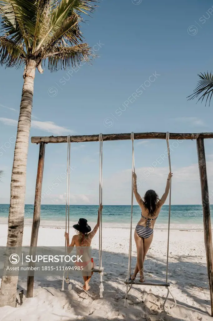 Mexico, Quintana Roo, Tulum, two young women on a swing on the beach