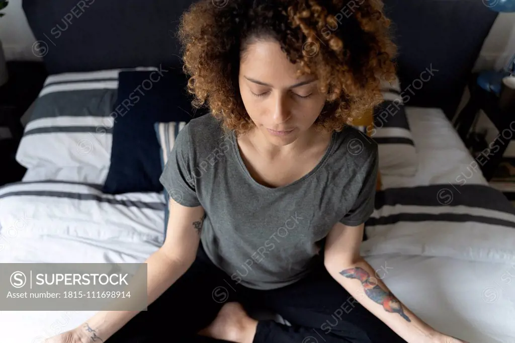 Woman practicing yoga, sitting on bed, meditating