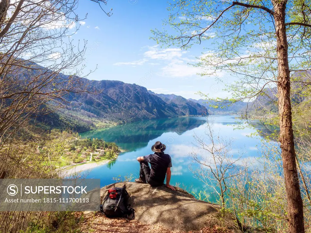Italy, Lombardy, spring at Lake Idro, hiker sitting on observation point
