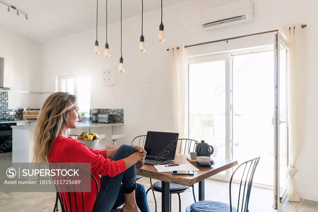 Woman using laptop on dining table in modern home