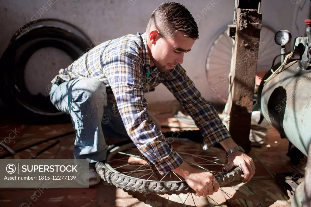 Cuba, Matanzas, Jaguey Grande, young man working at bicycle repair shop