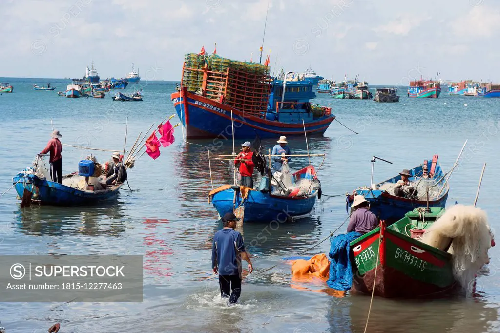 Vietnam, Vung Tau, fishermen sorting nets in harbor