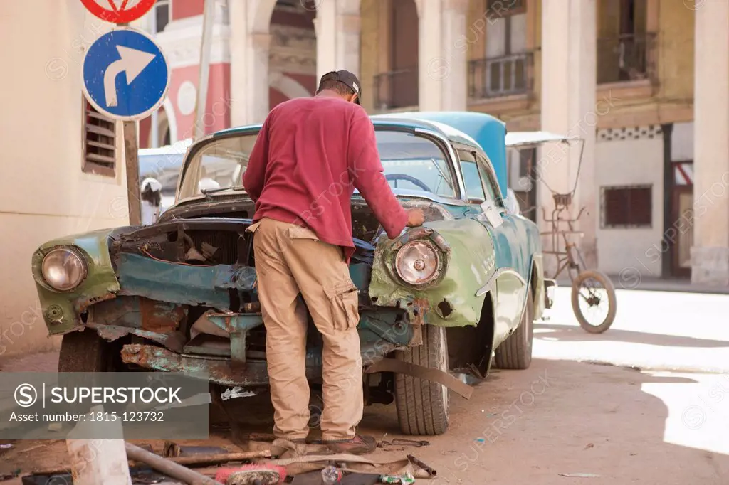 Cuba, Havana, Man trying to repair an old american car