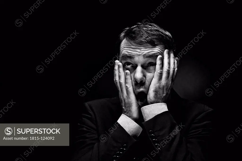 Mature man gesturing against black background, close up