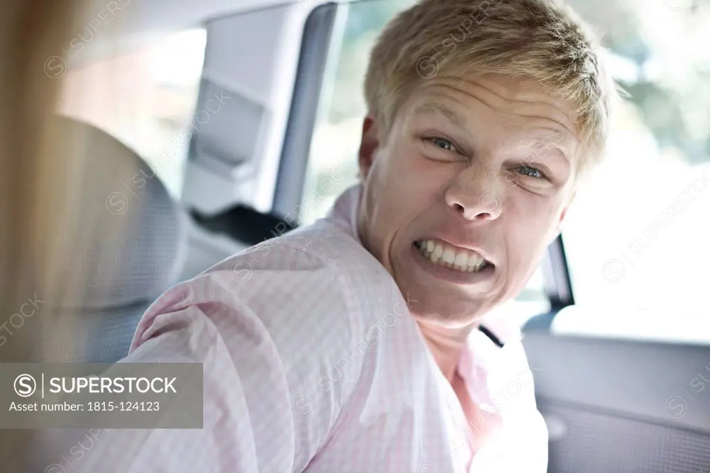 Germany, Duesseldorf, Young man making angry face in car
