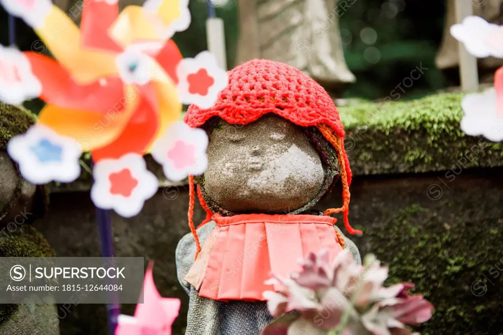 Japan, Tokyo, Jizo statue decorated with bib, knitted cap, flowers and pinwheel at Zojoji temple