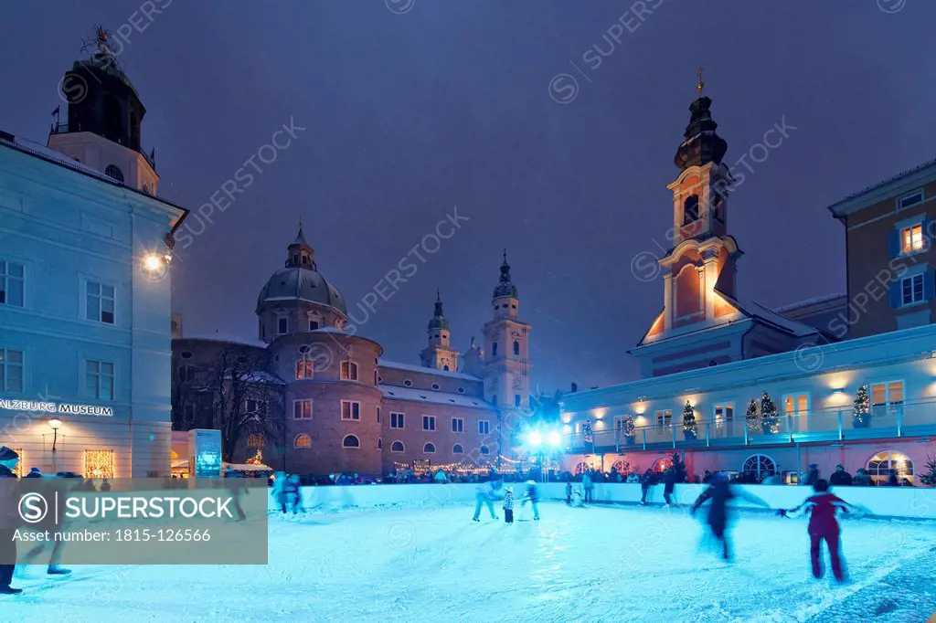 Austria, Salzburg, Ice skating place at Mozartplatz square, cathedral and St. Michael church in background